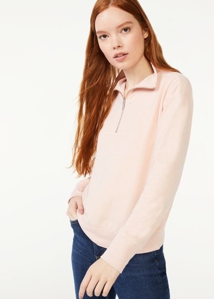 Model wearing pink zip top and jeans