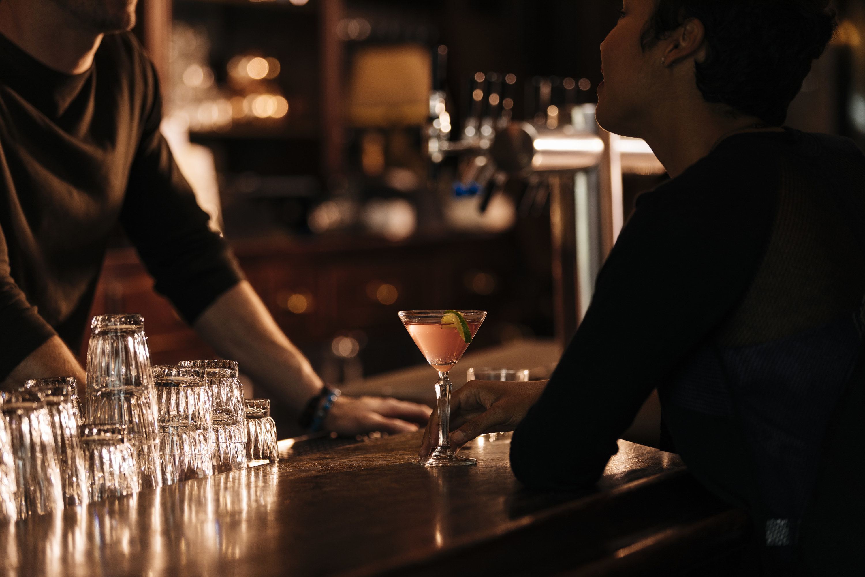 A dark bar with a bartender talking to a customer