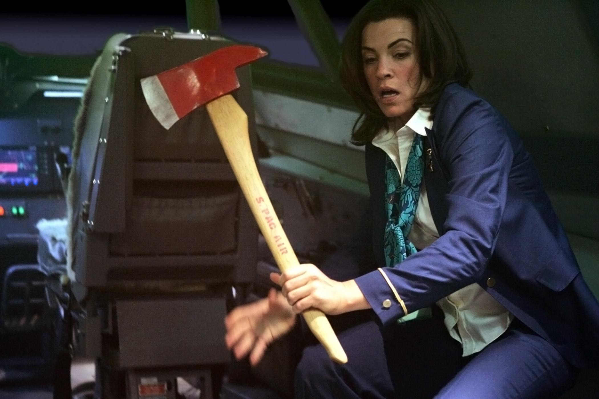 Julianna Margulies holds an ax on a plane while looking terrified and wearing a flight attendant uniform
