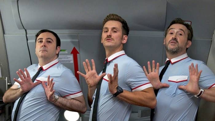 Three male flight attendants dance on a plane
