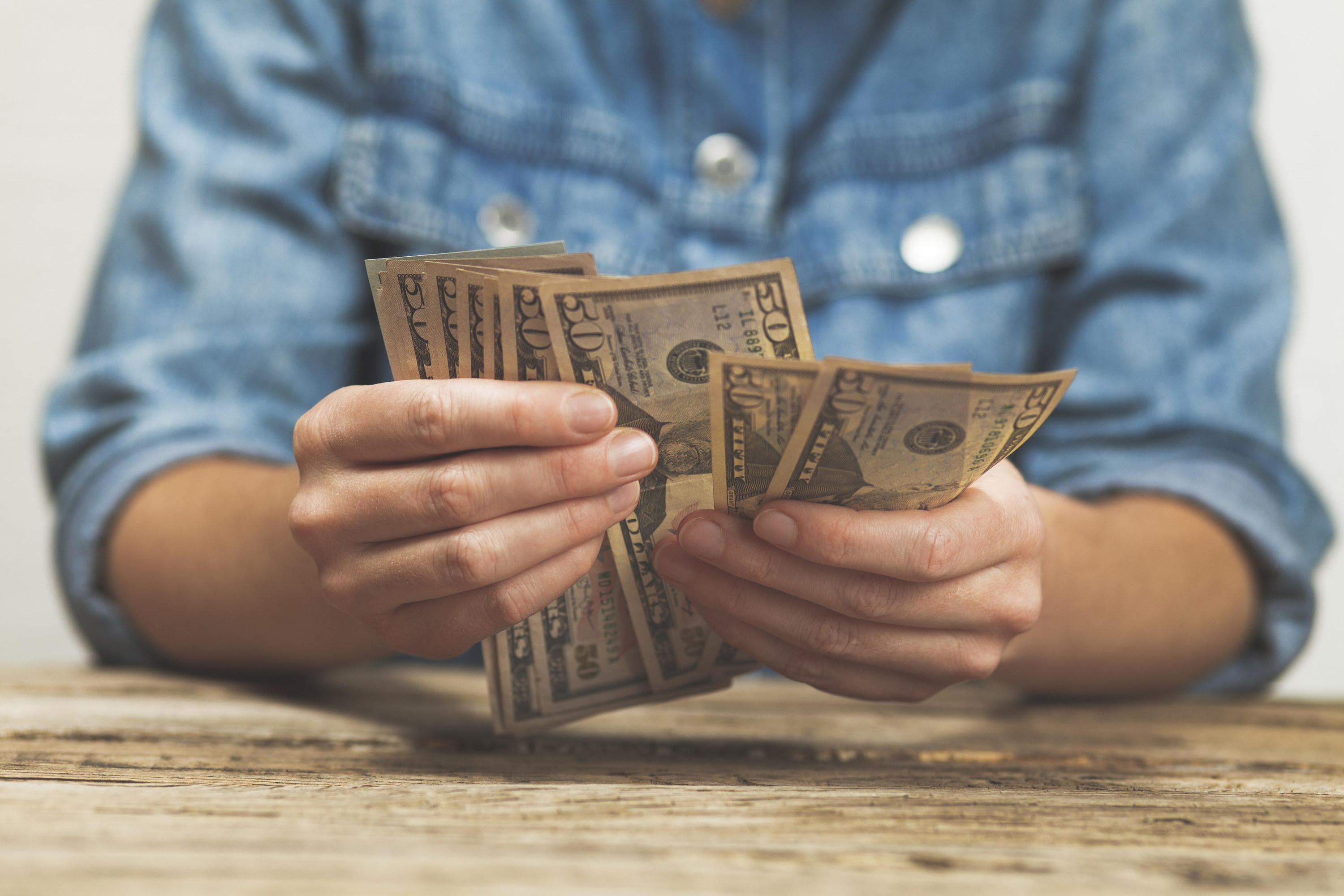 A person counting money sitting at a table