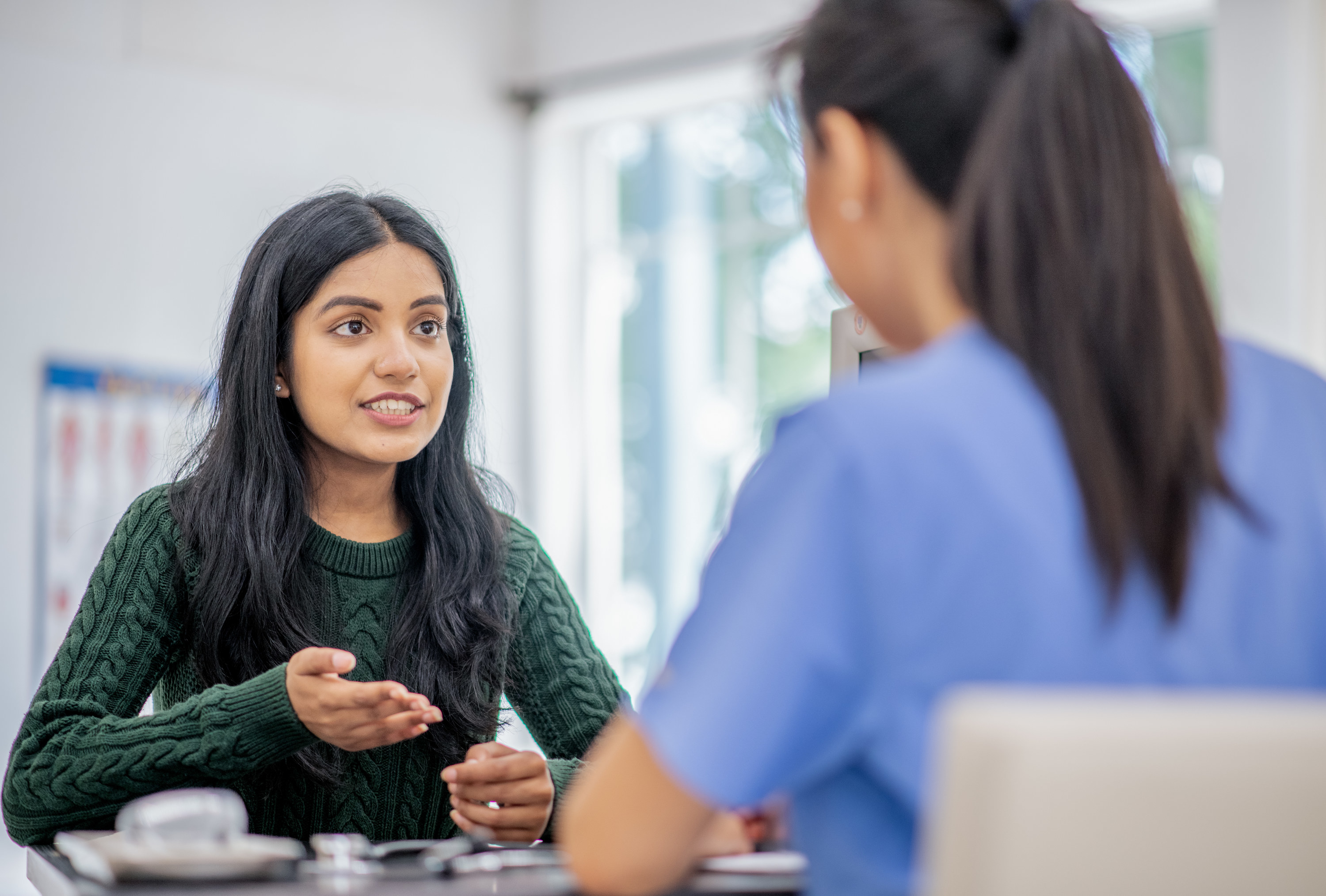 A young woman visits a specialist to consult, appearing optimistic in discussion