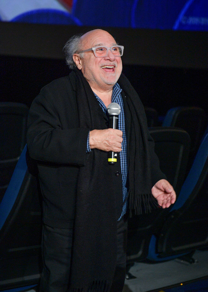 Danny DeVito smiling and holding a mic