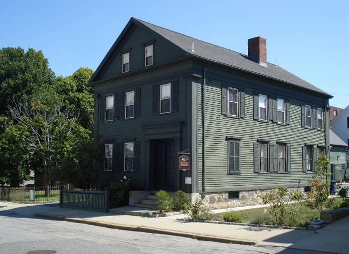 three-story house on a suburban street with at least 15 windows and a brick chimney