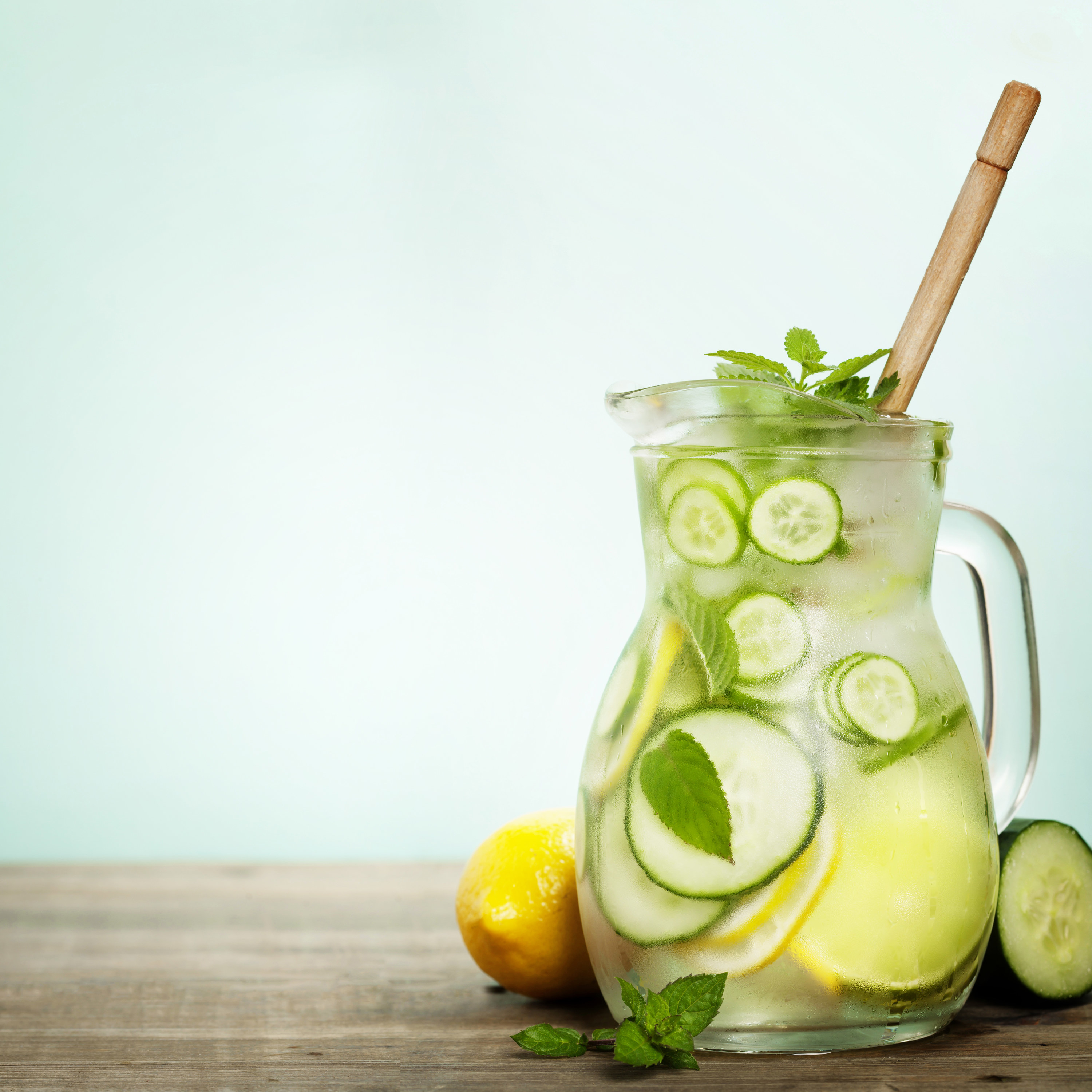 pitcher of water with sliced cucumber and lemons in it