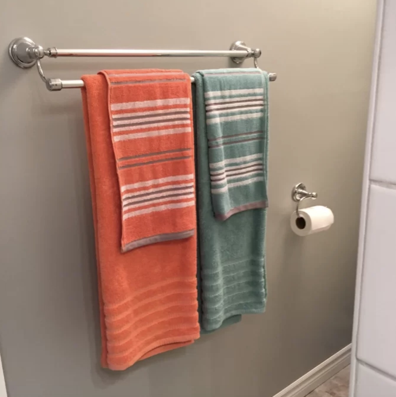 The orange and teal striped towels are hung in a bathroom