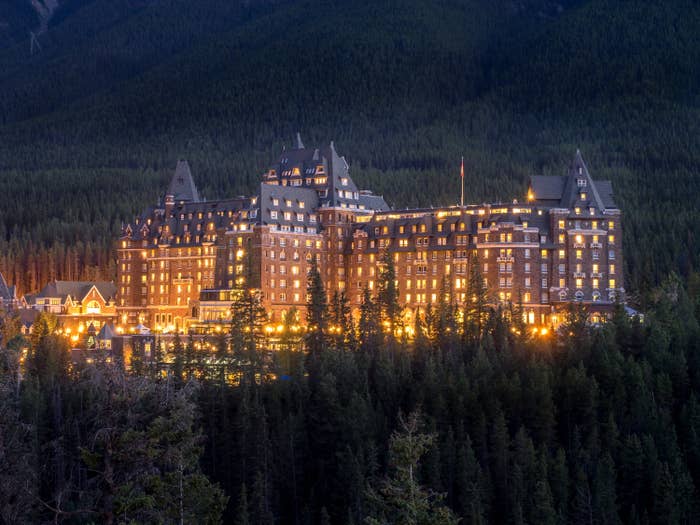gigantic hotel with hundreds of windows on the side of a mountain surrounded by trees
