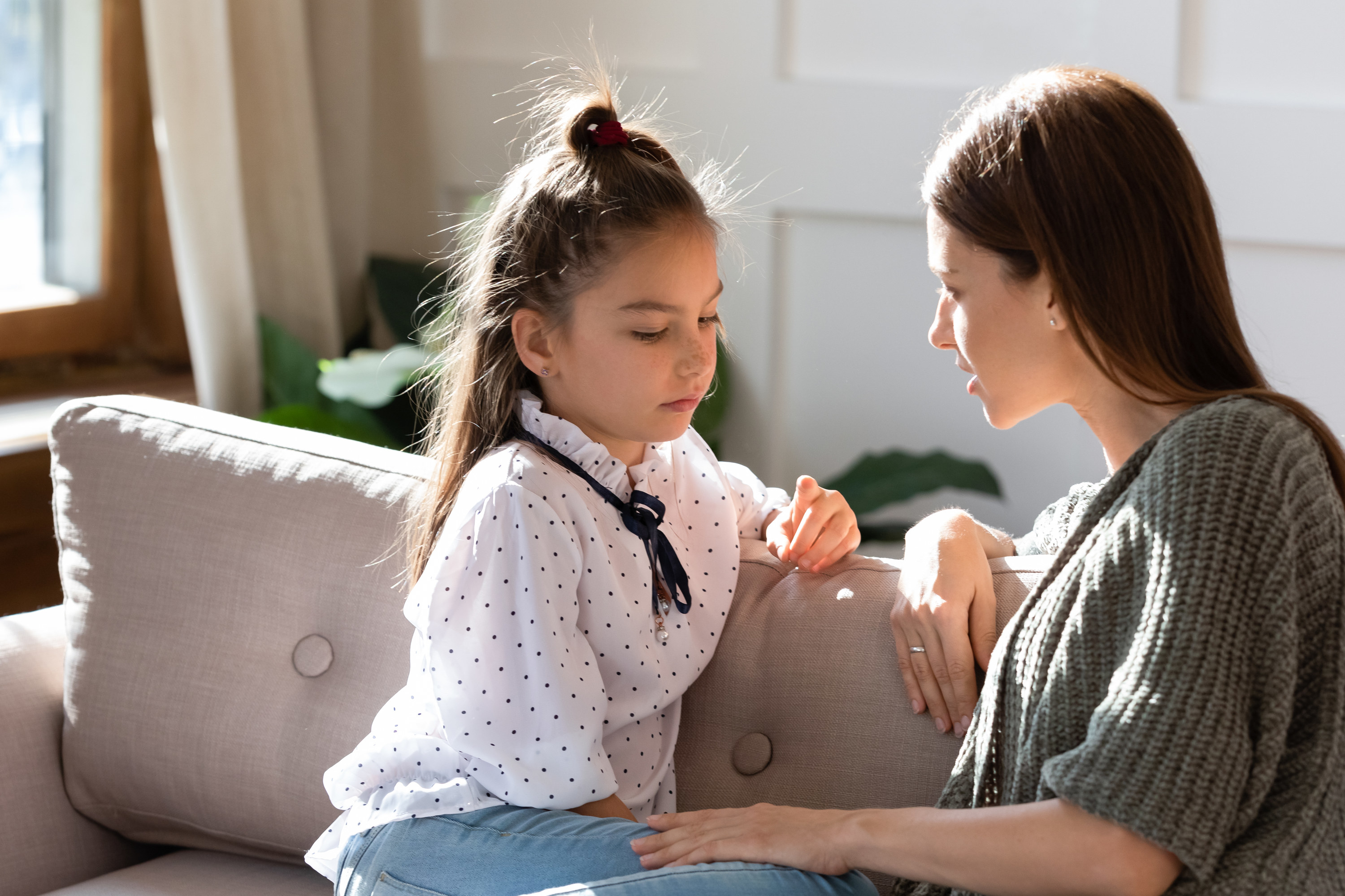 A young girl with her mom on the couch