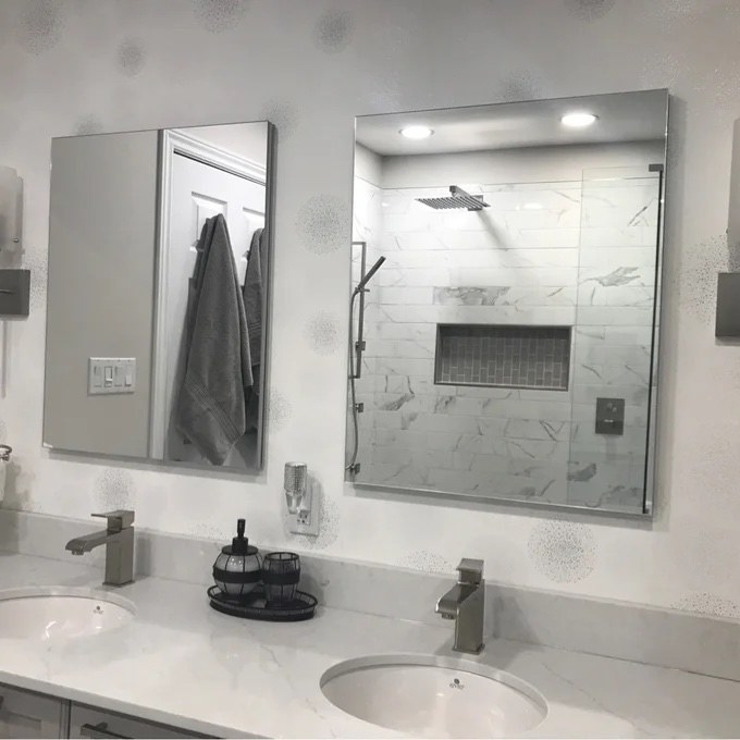 two frameless mirrored medicine cabinets hanging in a bathroom