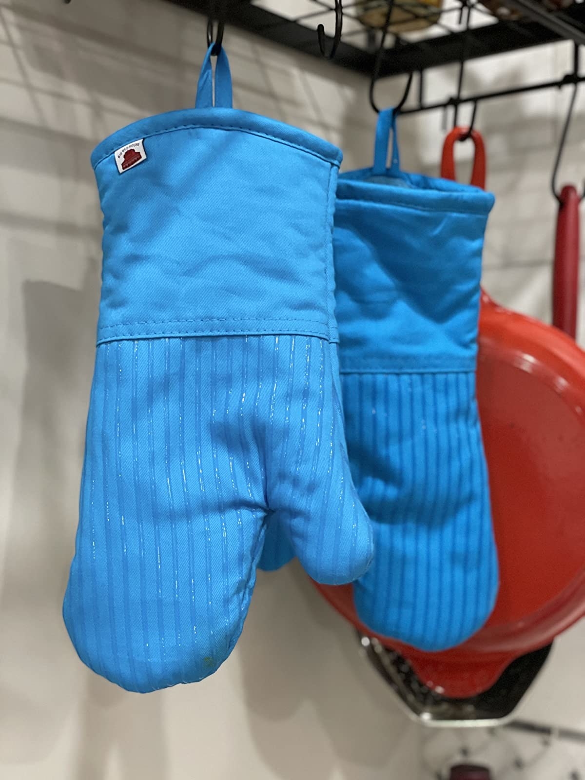reviewer photo of two blue oven mitts hanging on a rack