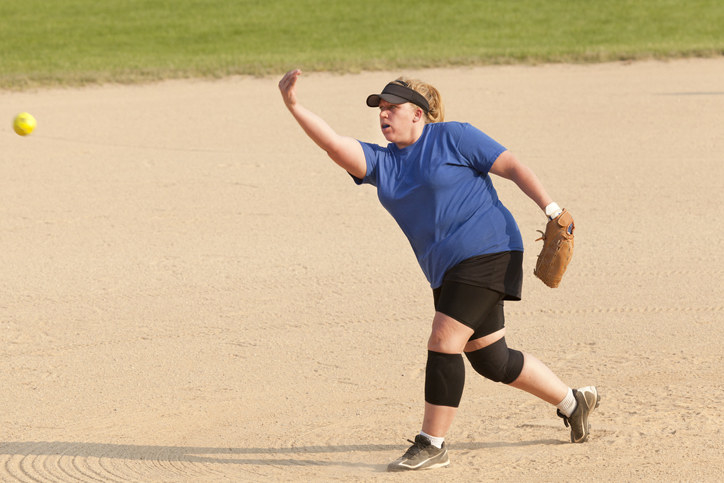 A woman throwing a softball.