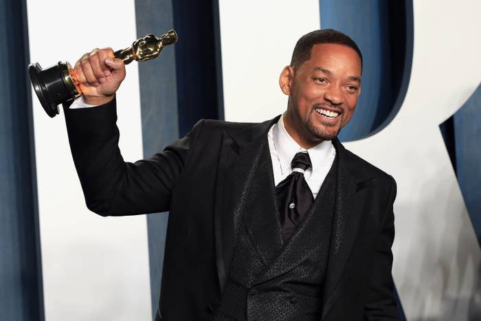 Will Smith smiles and holds up his Oscar