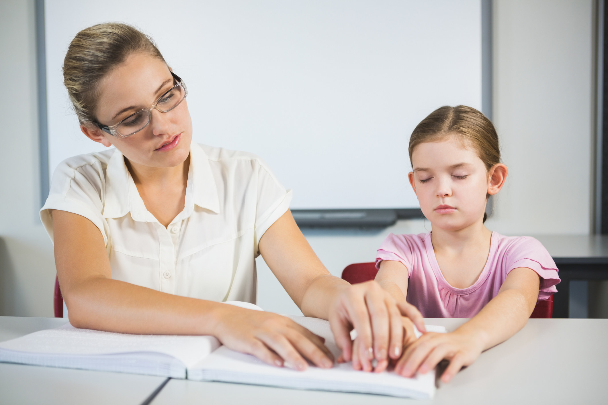 a teacher helping a student read brail