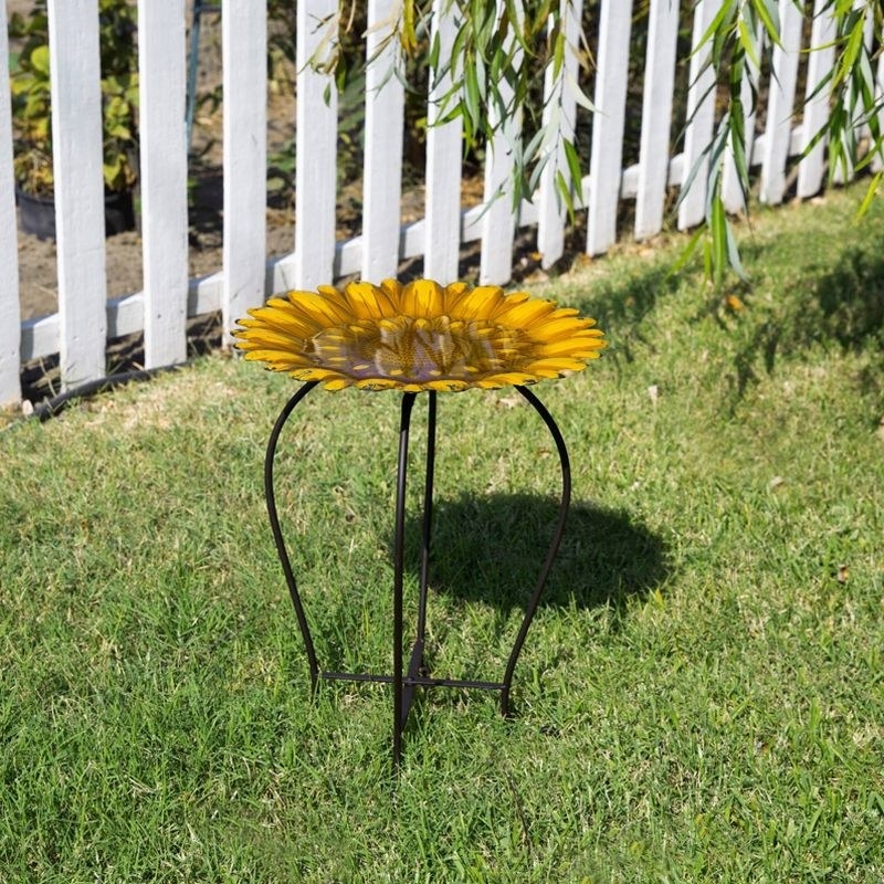 an iron/glass sunflower birdbath out in a backyard