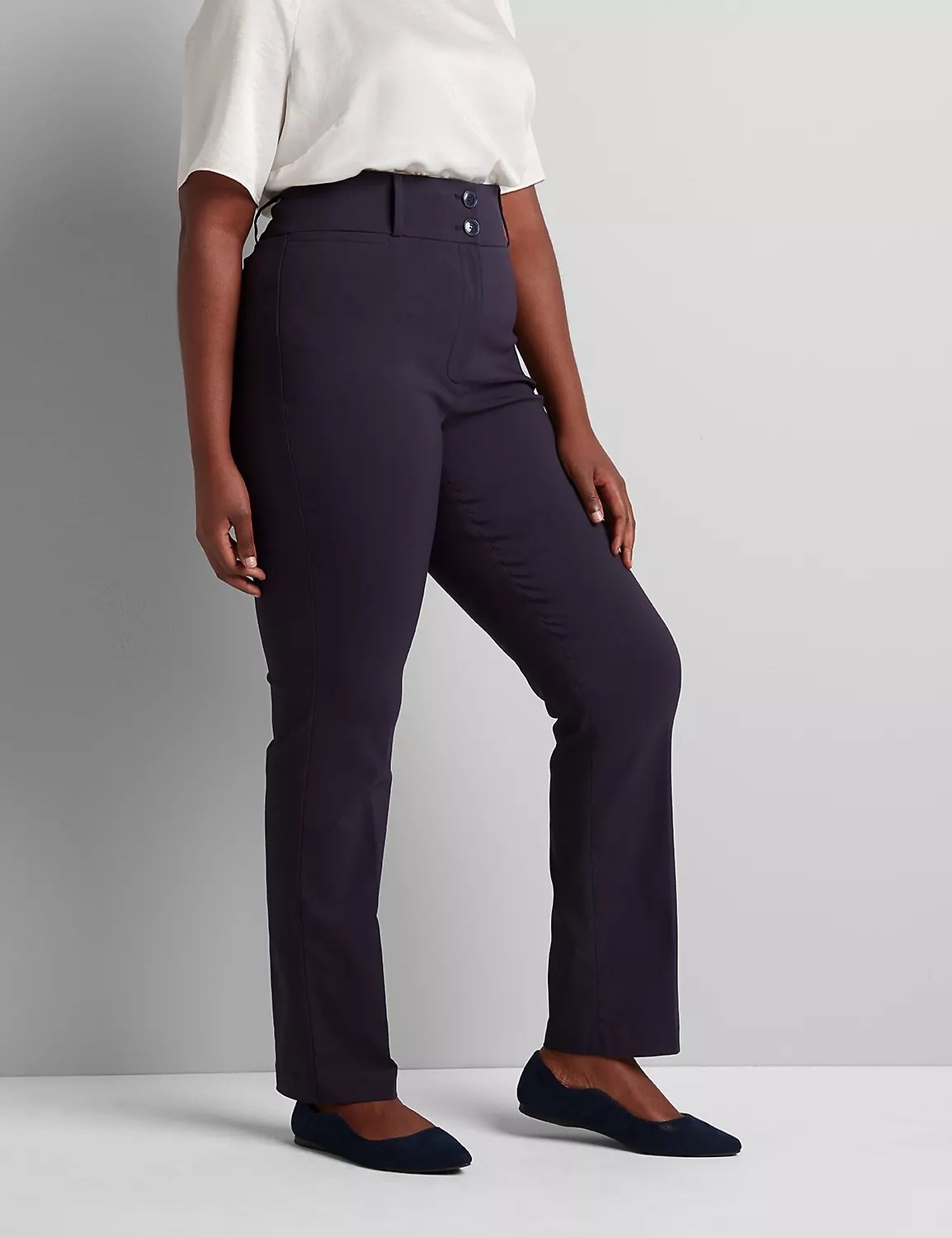 Model wearing navy pants with black shoes and a white top