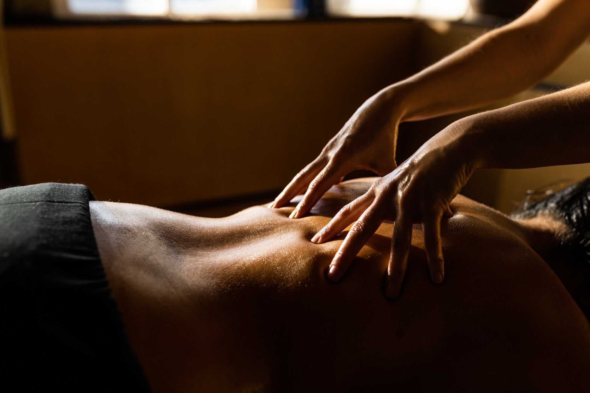 Person massaging a man's back as he lies facedown. 