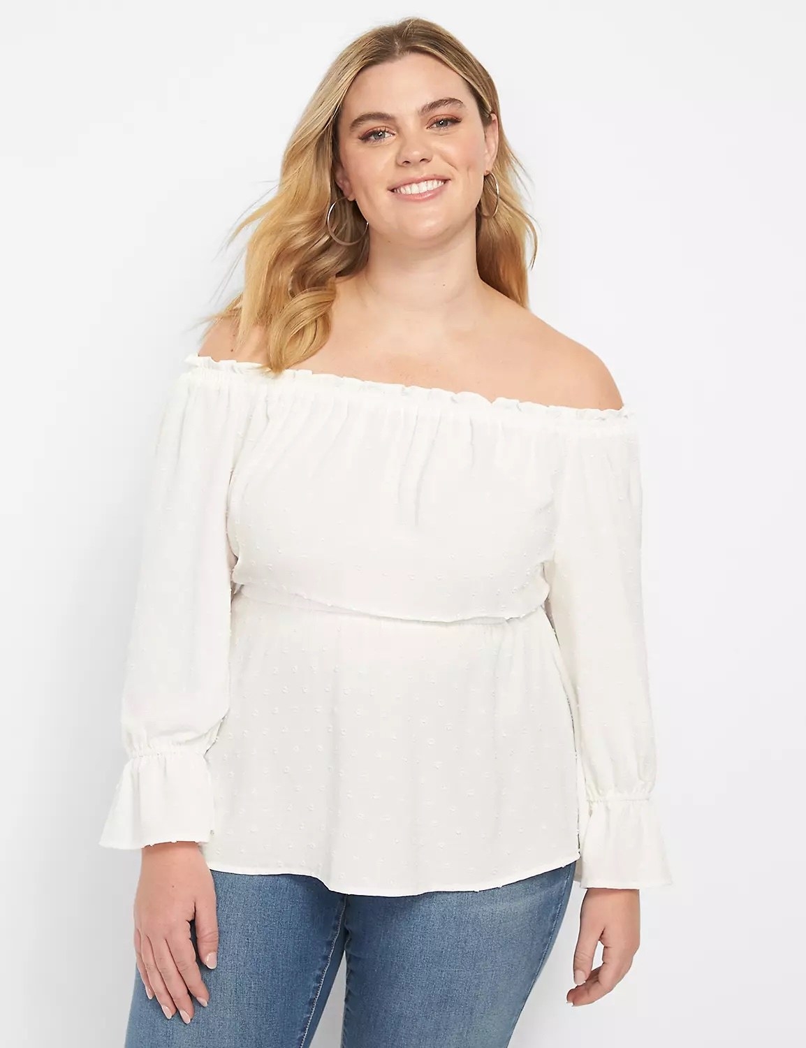 Model wearing off the shoulder long white top with blue jeans