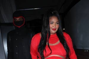 Lizzo walks in front of the masked man