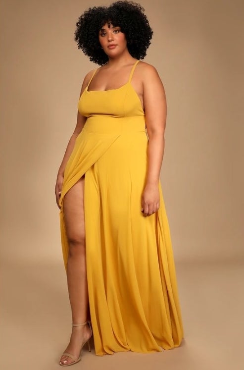 An image of a model wearing a yellow backless maxi dress