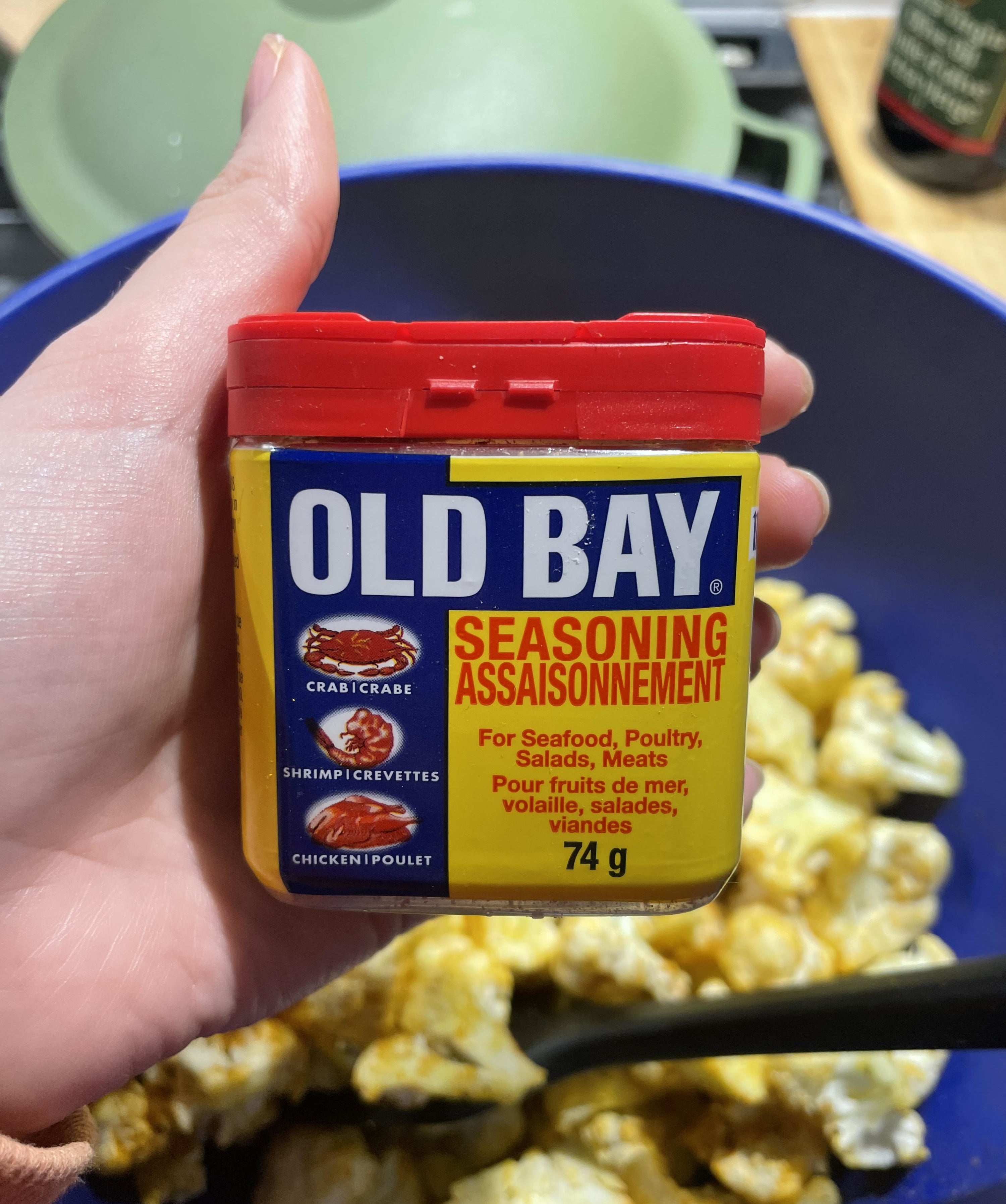 Alice holding a shaker of Old Bay seasoning over a bowl of cauliflower