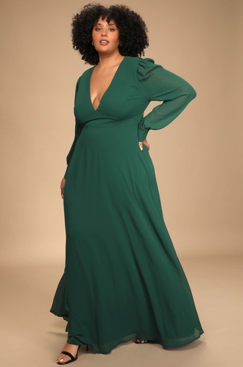 An image of a model wearing a long-sleeve maxi dress with long sheer sleeves, a V-neck line, and a low back