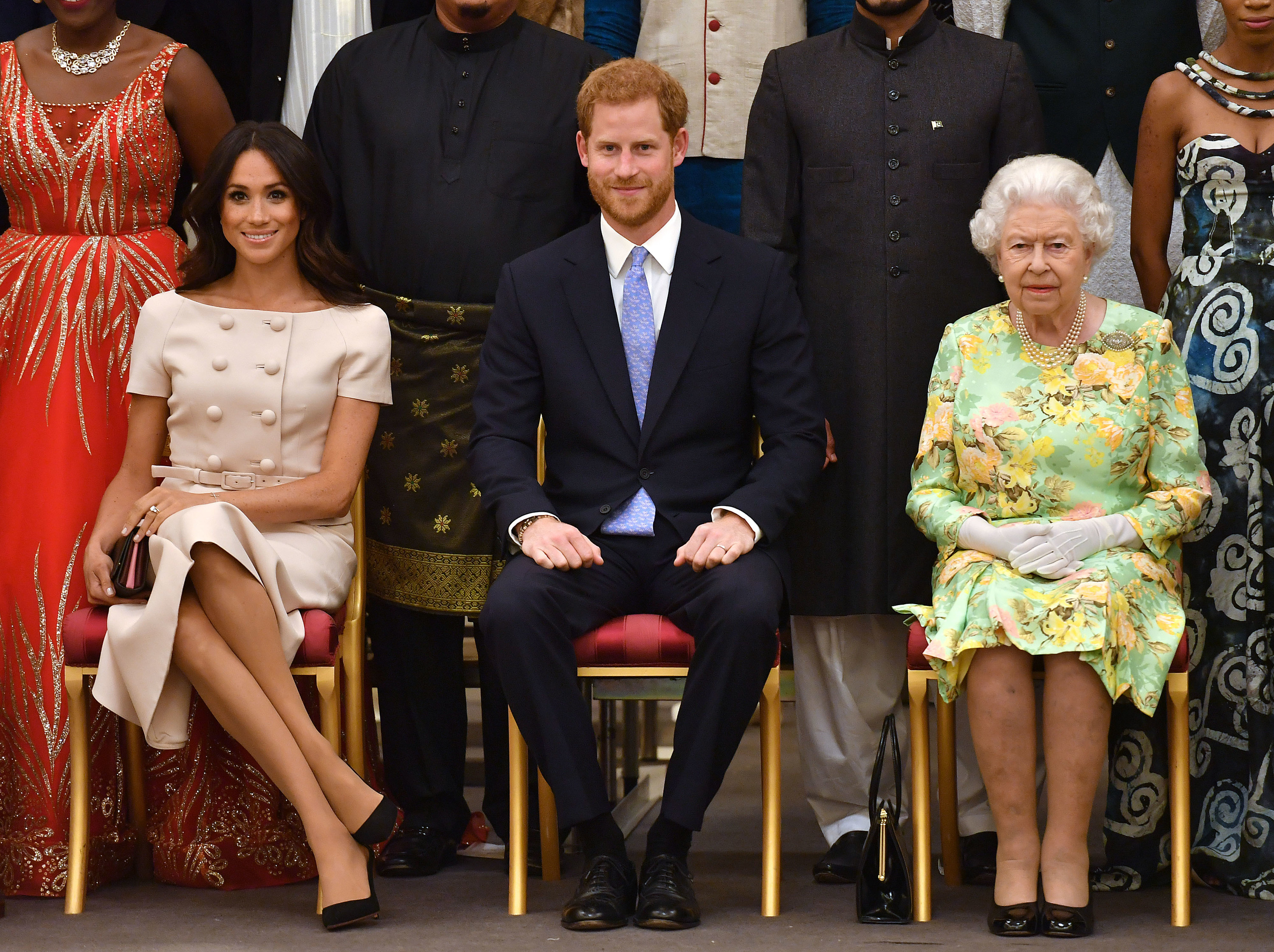 Meghan, Harry and the queen sit in chairs at an event