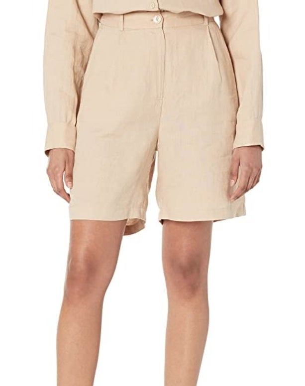 A model wearing a pair of nude linen Bermuda shorts