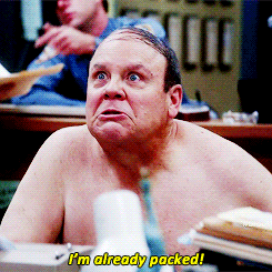 Michael Hitchcock from Brooklyn 99, shirtless, standing and holding a clear bag while declaring , &quot;I&#x27;m already packed&quot;