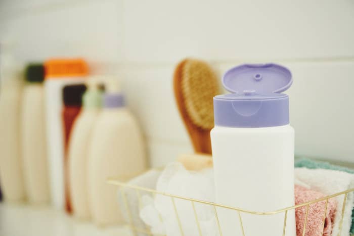 close-up of a shampoo bottle and loofahs in a shower caddy