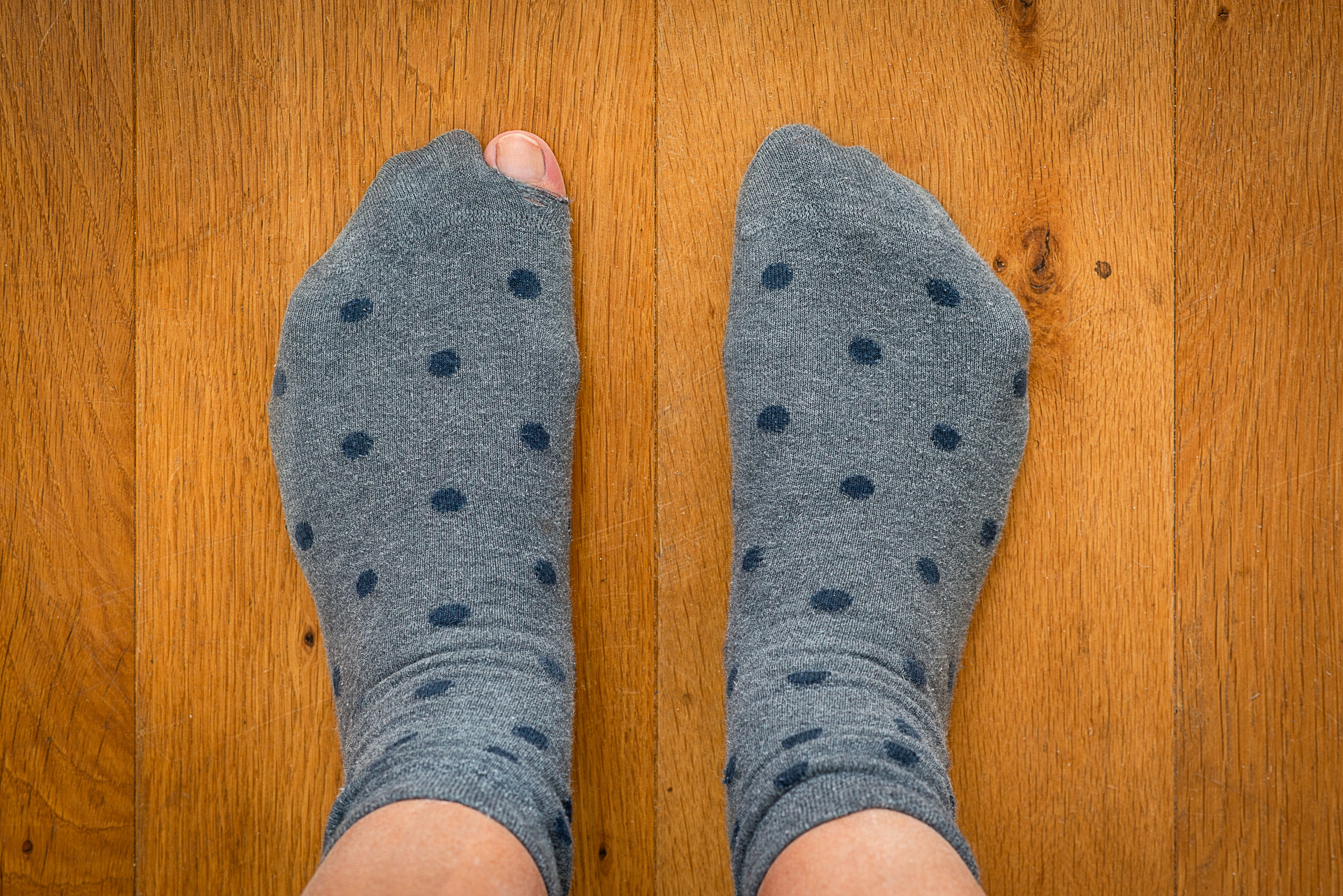 person wearing socks with a hole in one toe