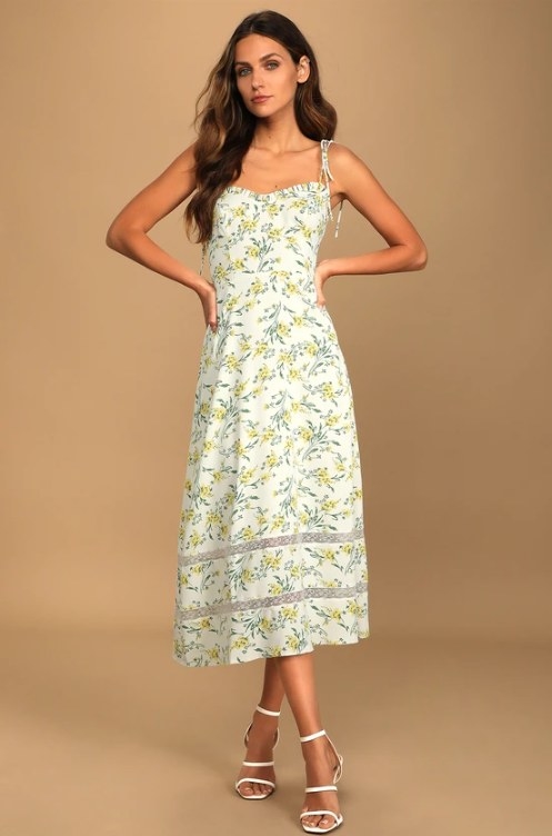 An image of a model wearing a floral tie-strap midi dress with a ruffled sweetheart neckline