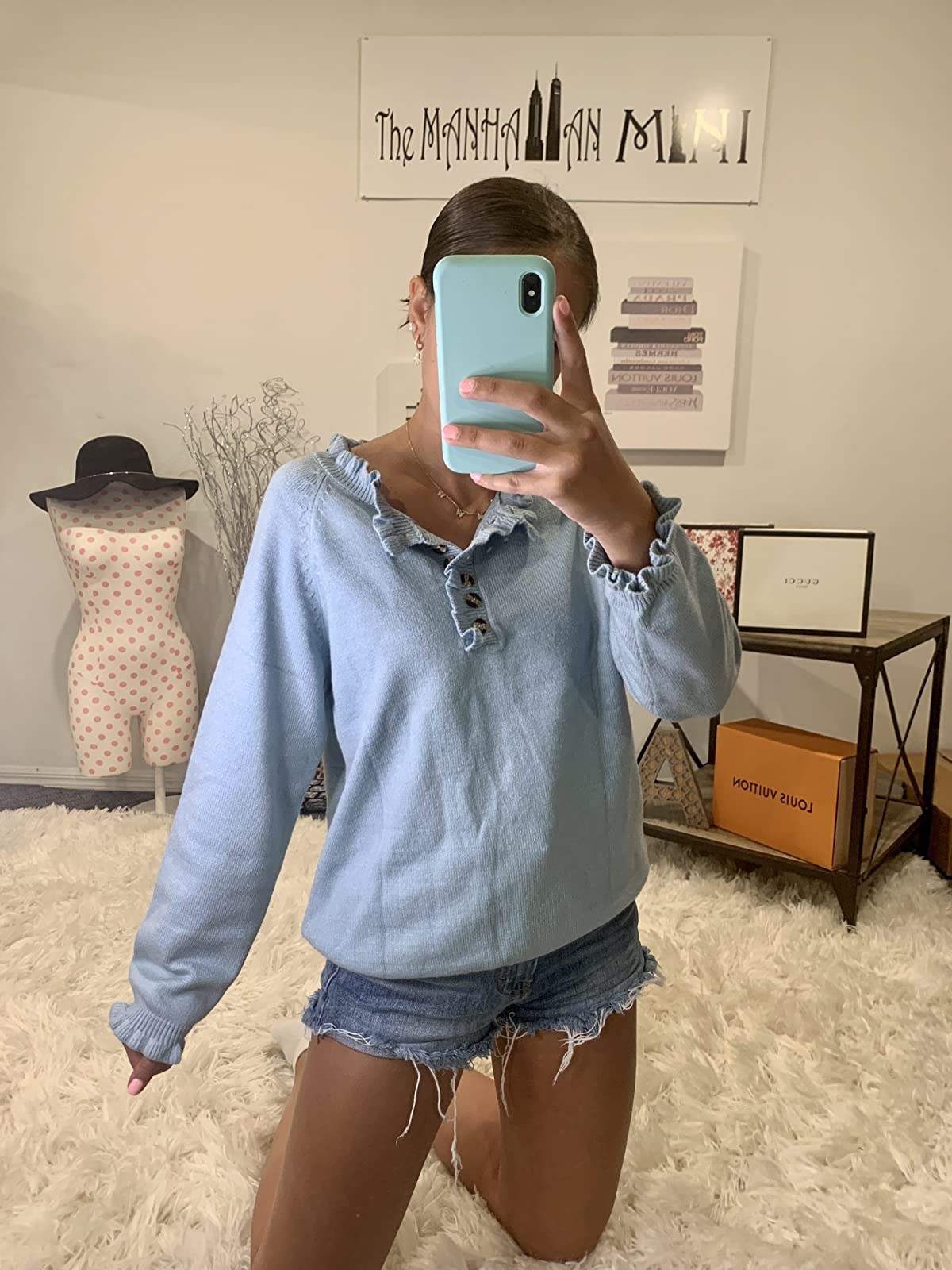 Reviewer wearing light blue sweater and denim shorts
