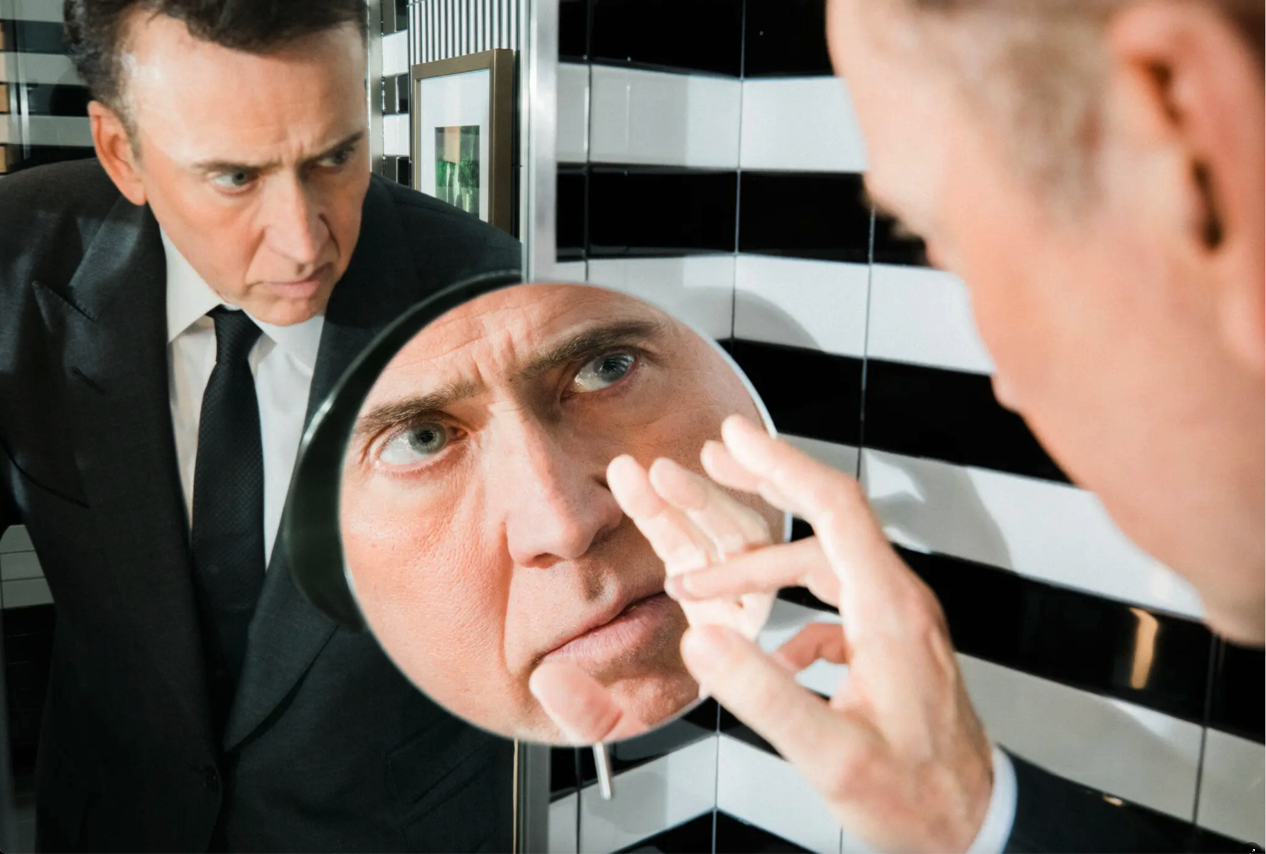 Nicolas Cage  looks at himself in the mirror as a close-up of him touching his face appears in a circle in the middle