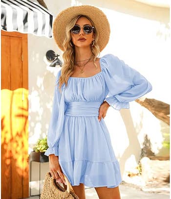 a m wearing a blue off-the-shoulder dress and a raffia hat