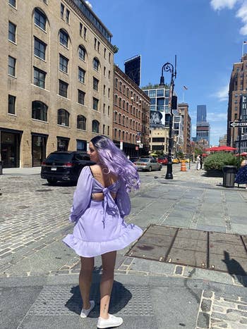 a woman wearing a lavender midi dress twirling in the street