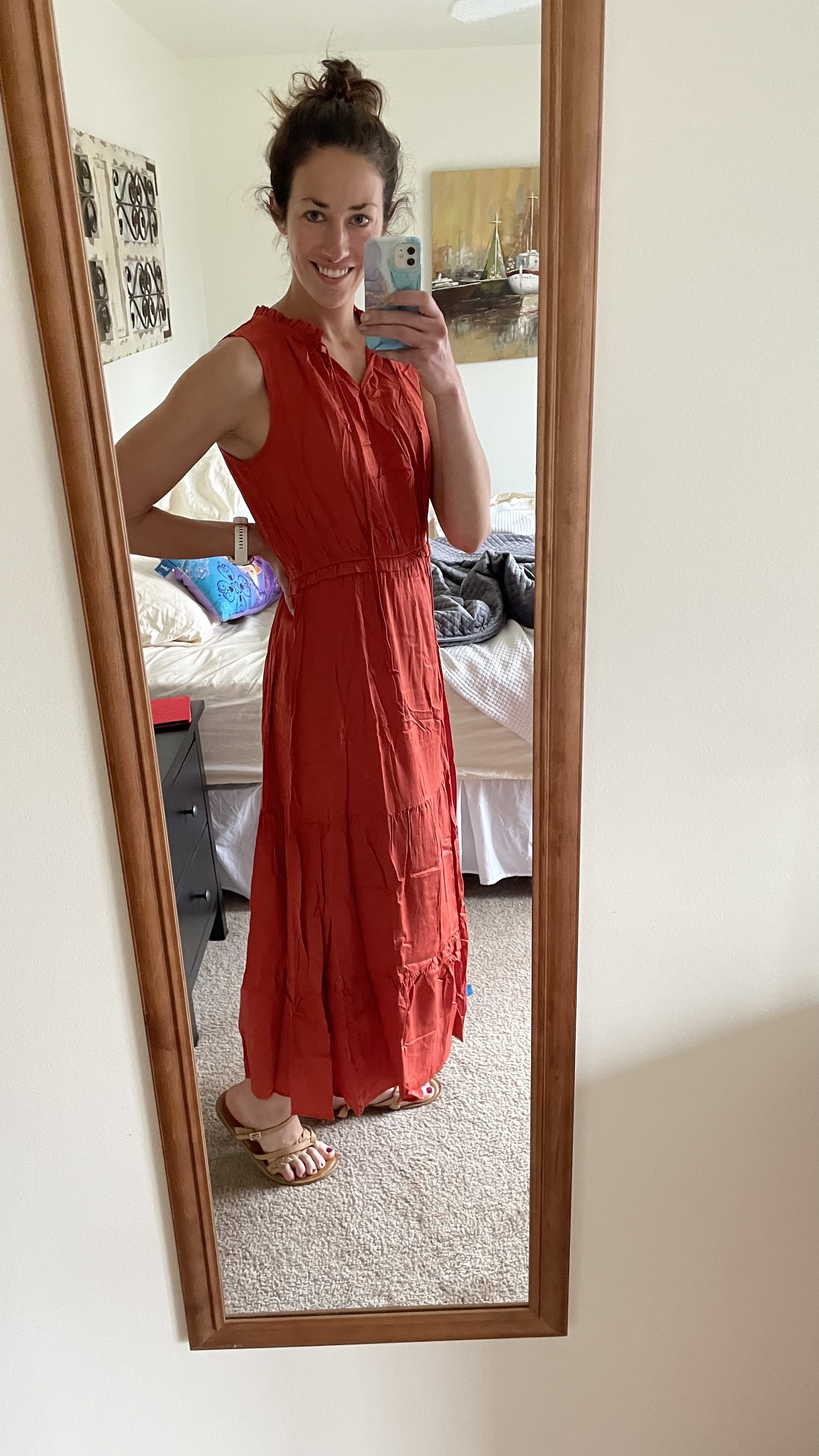 a woman taking a mirror selfie in a bedroom wearing a red maxi dress