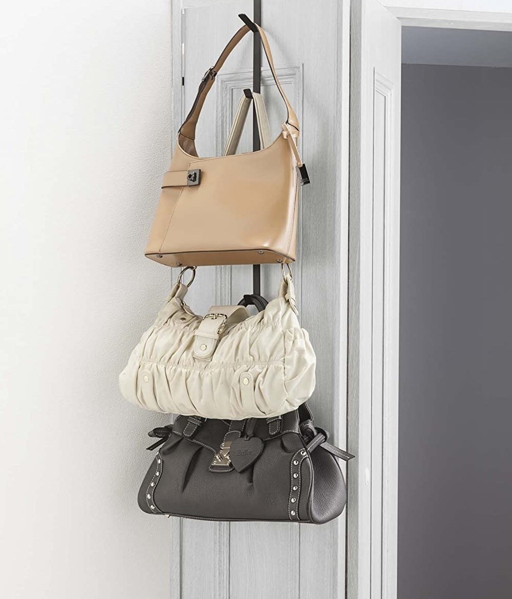 three purses hanging off the vertical door hanger