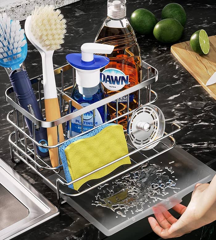 a hand pulling out a removable tray from under a kitchen sink caddy filled with cleaning supplies
