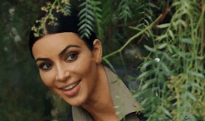 Kim Kardashian poking her head out from behind a bush