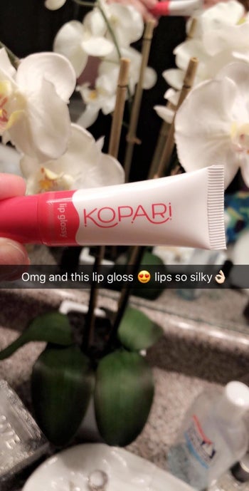 Reviewer holding Kopari lip gloss