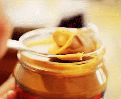 Someone scooping peanut butter out of a jar