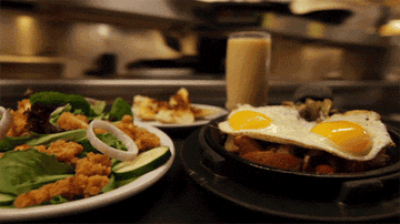 Plates of food, including eggs sunny-side up, are brought out in a restaurant