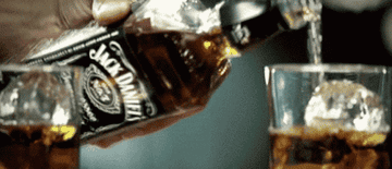 Someone pours Jack Daniel&#x27;s into a glass