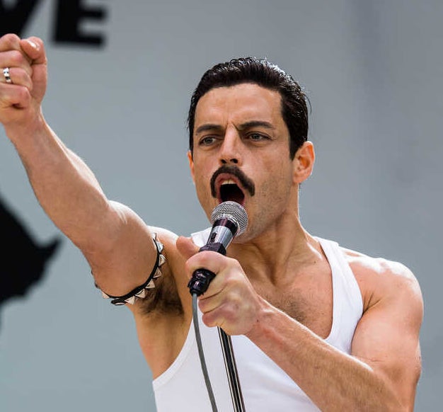 Rami Malek acting as Freddie Mercury and singing into a mic