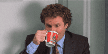 Will Ferrell in a suit drinking coffee and making a disgusted face