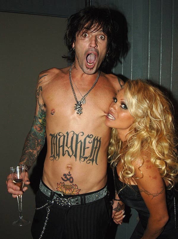 Tommy Lee looking surprised and Pamela Anderson biting his nipple ring