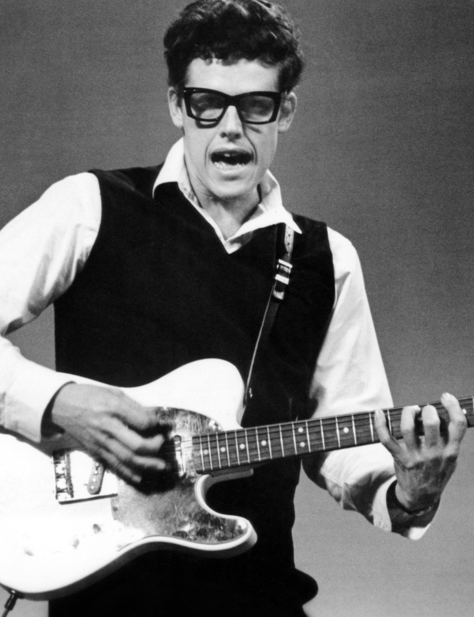 Gary Busey playing guitar and dressed like Buddy Holly