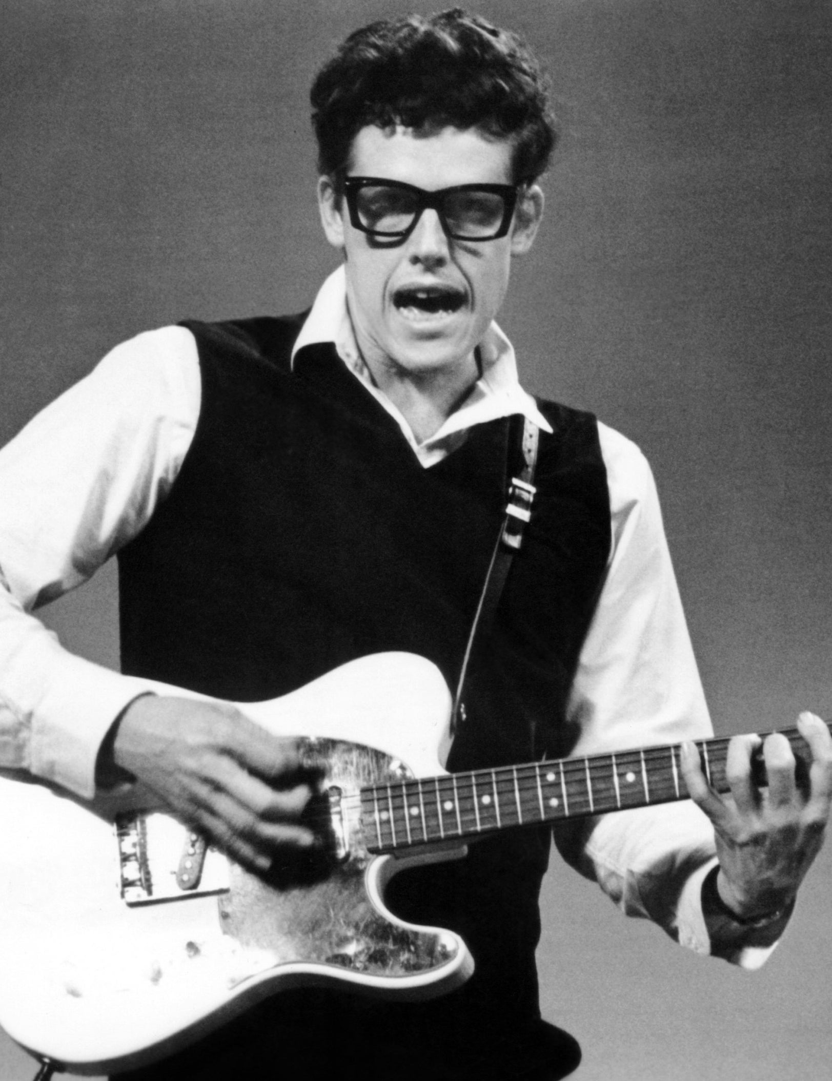 Gary Busey playing guitar and dressed like Buddy Holly
