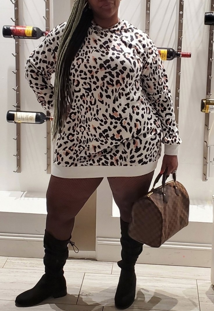Reviewer wearing white leopard print sweatshirt dress with black knee high boots