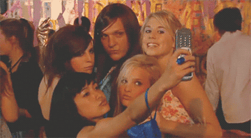 a group poses for a selfie on a flip phone